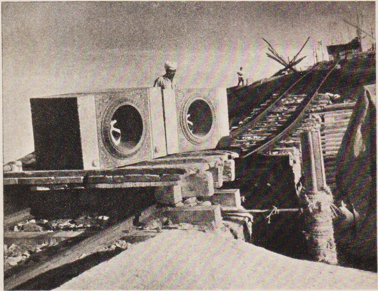 Dressed stones placed on a trolley being hauled up to the memorial-site by means of wire ropes and a winch.